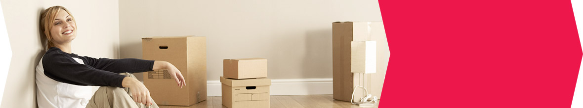 A young blond woman leaning on the wall next to a stack of moving boxes