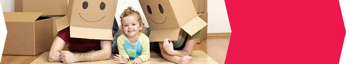 Parents and their toddler on the floor. Both parents are wearing smile faces made of moving boxes