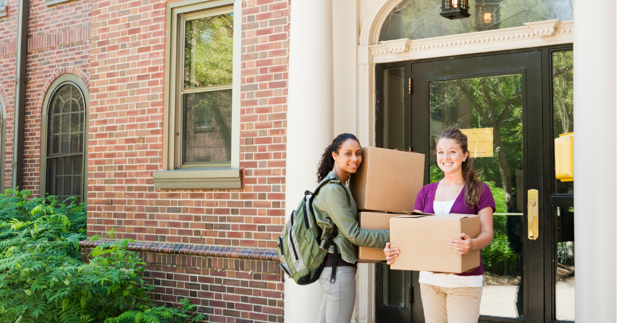 A couple of friends holding moving boxes about to enter their new home