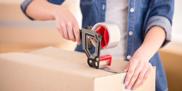 Person sealing a cardboard box with packing tape