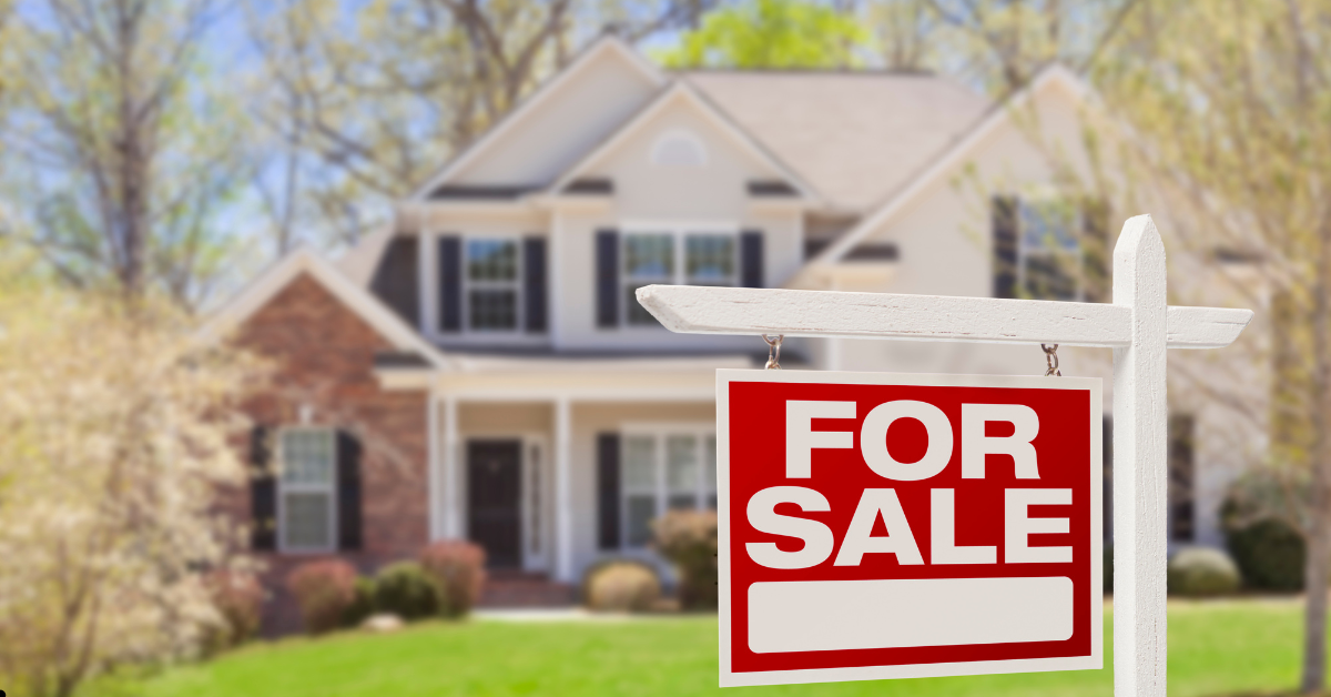 For sale red and white signage with a big home in the background