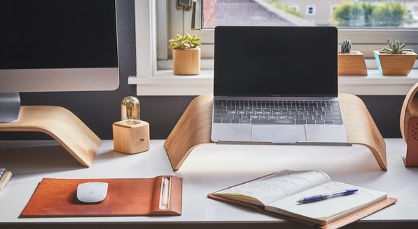 Organised desk with a laptop, notebook, and accessories.