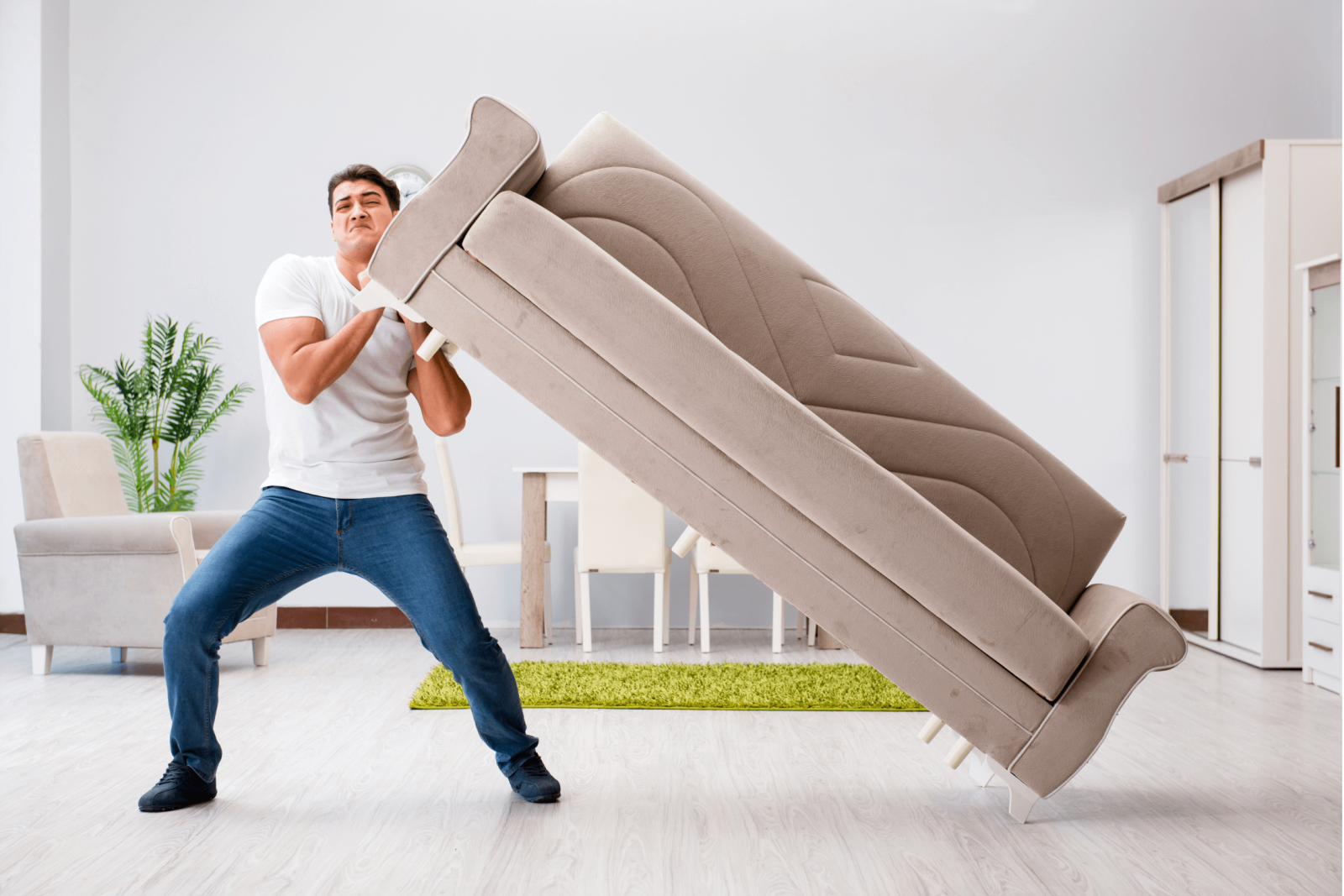 A man trying to lift a heavy light coloured sofa