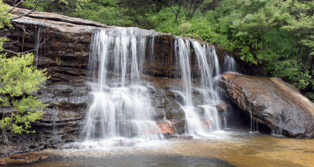 Waterfall cascading over rocks surrounded by the bush in the Blue Mountains.