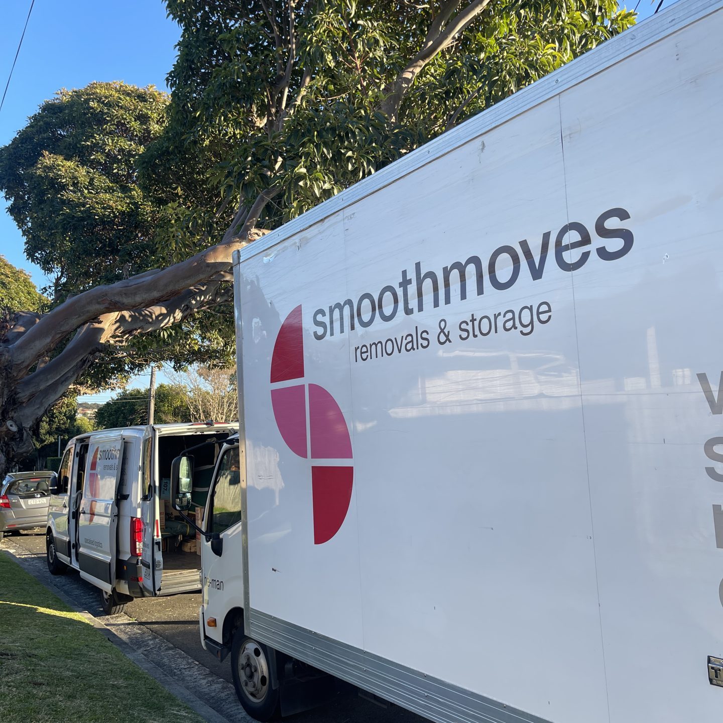 A Smoothmoves truck and van parked on thre streed, on the process of loading boxes